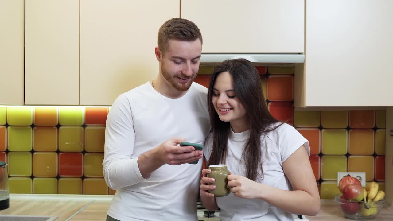 年轻夫妇有乐趣看手机上的照片视频下载