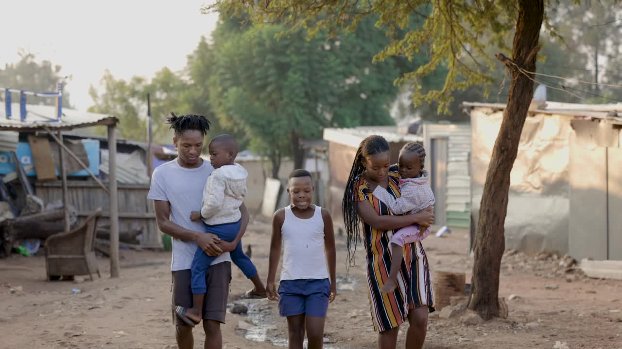 贫困。不平等。贫穷的非洲黑人家庭行走在一个典型的贫民窟地区，显示了非洲环境的贫困和水的浪费视频素材