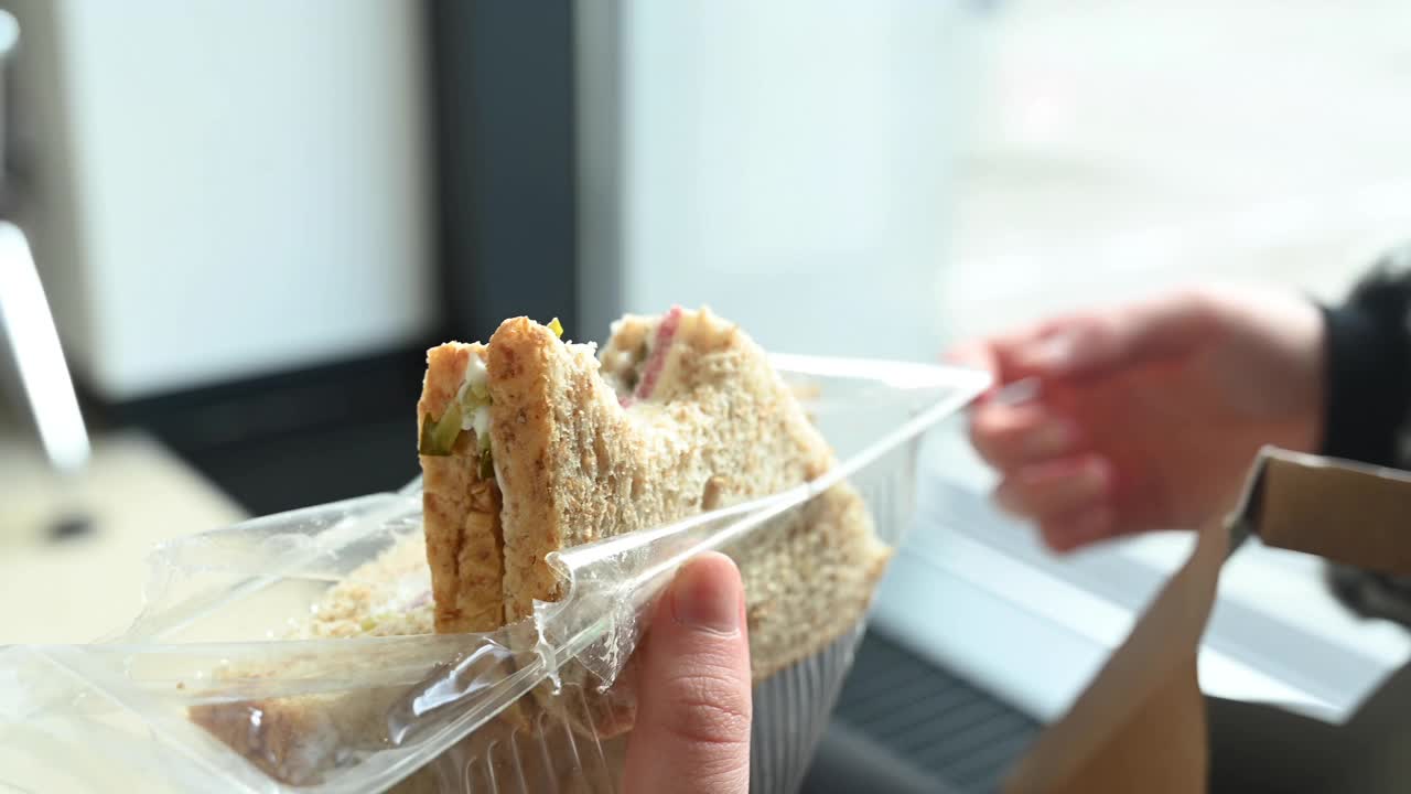 在机场候机室，一个陌生的年轻女子的手拿着一个三明治视频下载