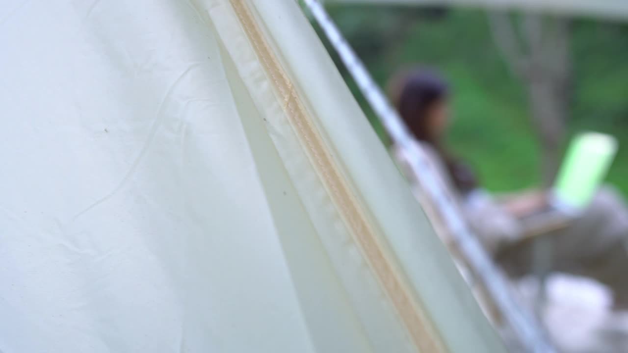 亚洲妇女工作在笔记本电脑上，坐在椅子上露营，在野外，色度键，平移拍摄视频下载