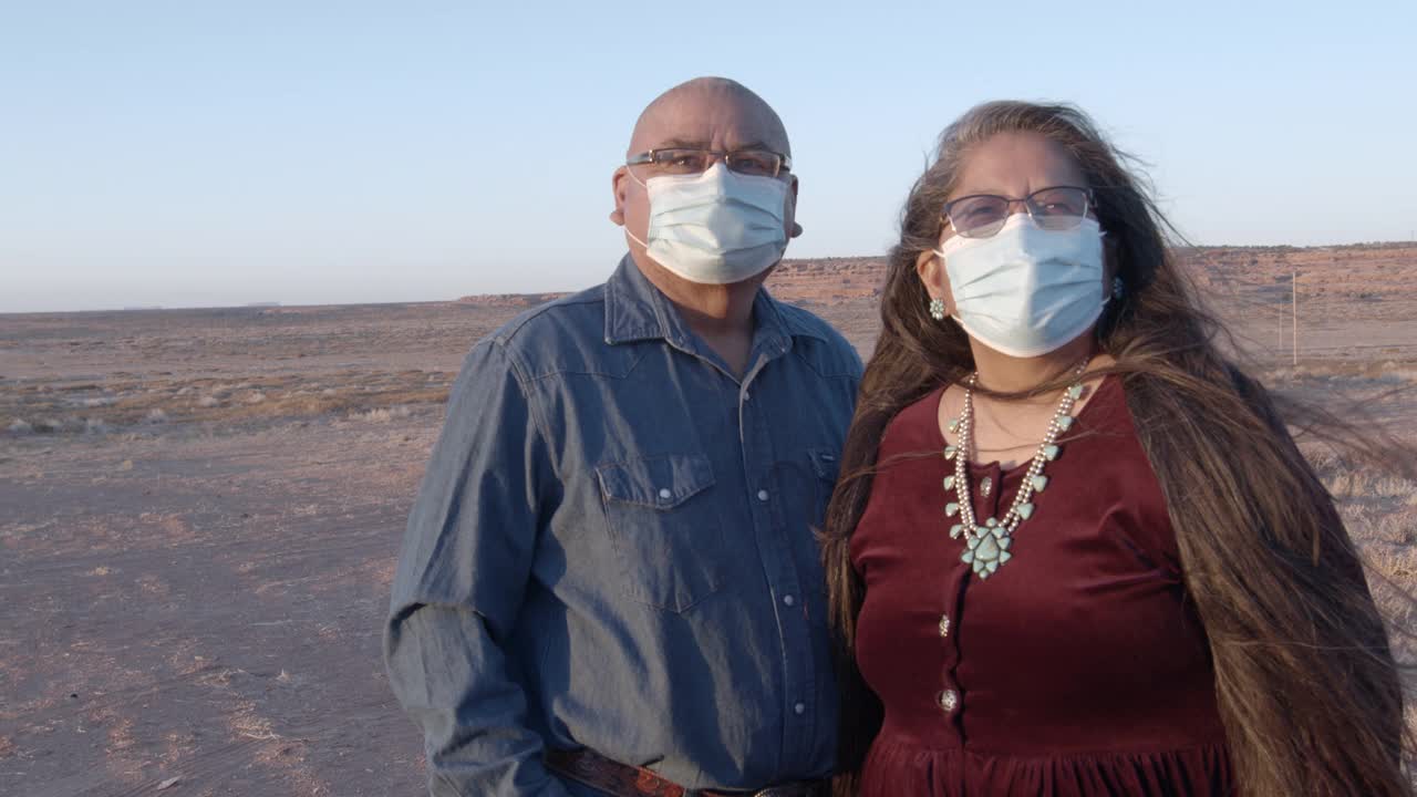 在犹他州纪念碑谷的家附近戴着防护面具的美国土著夫妇视频素材
