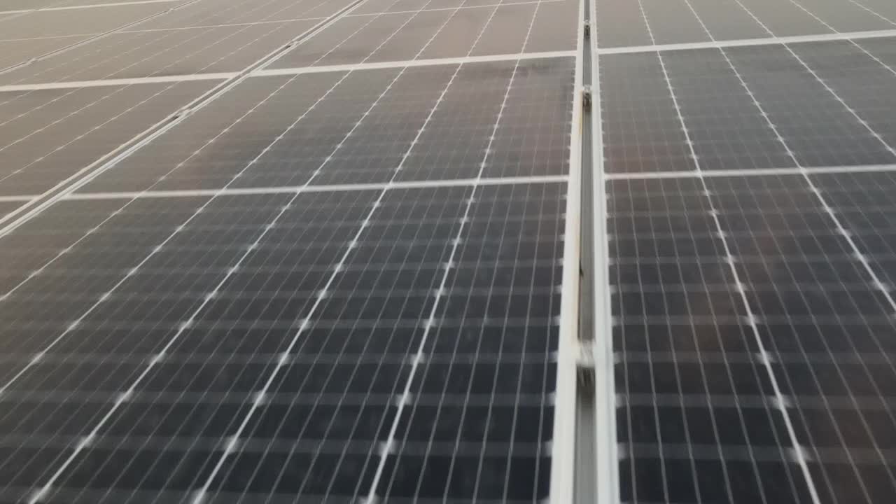 无人机视图移动真正接近大型太阳能电池板阵列4K鸟瞰图太阳能电池板农场(太阳能电池)与阳光。视频素材