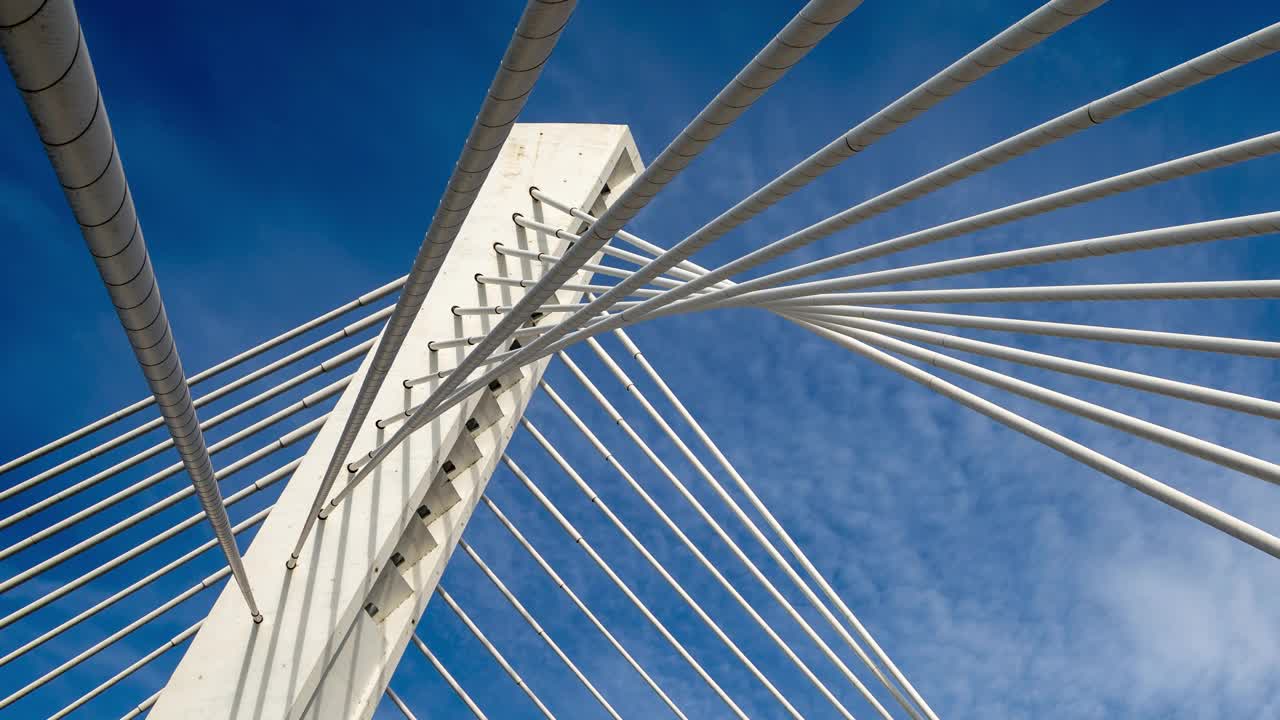 斜拉桥的塔架在蓝天中快速移动的白云下，由塔顶发出的绳索或绳索支撑。抽象的时间流逝。视频下载