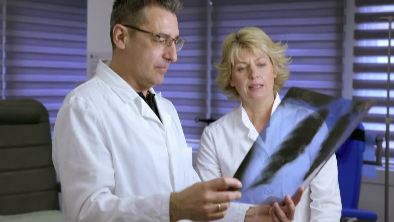 医生和他的女同事拿着x光片检查肺炎的原因视频素材