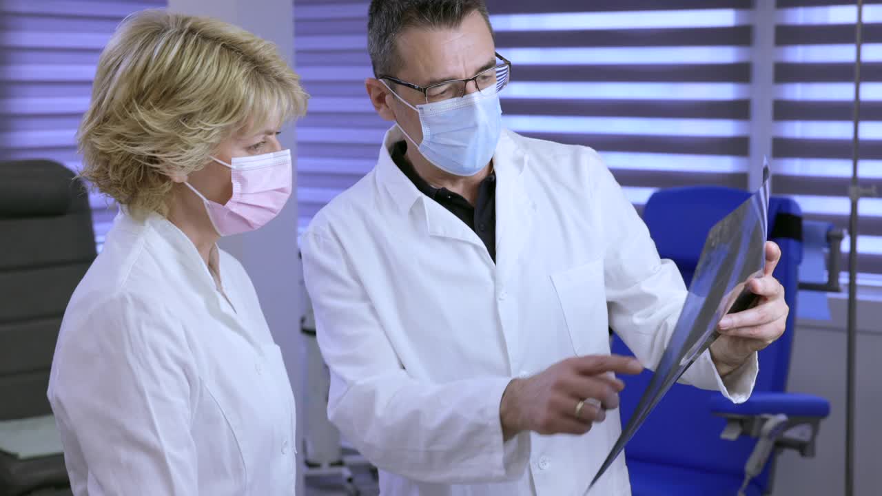 医生和他的女同事戴上防护口罩并进行x光检查视频素材