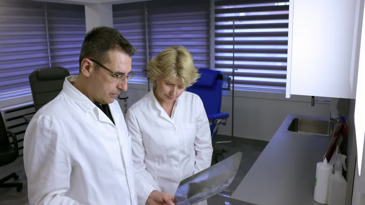 医生和他的女同事在用反光镜检查x射线视频素材