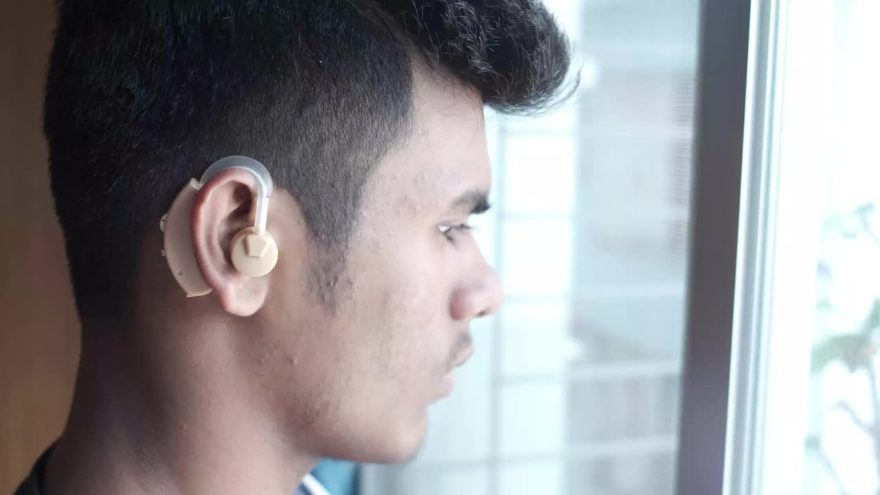 助听器概念，一个听力有问题的年轻人。视频下载