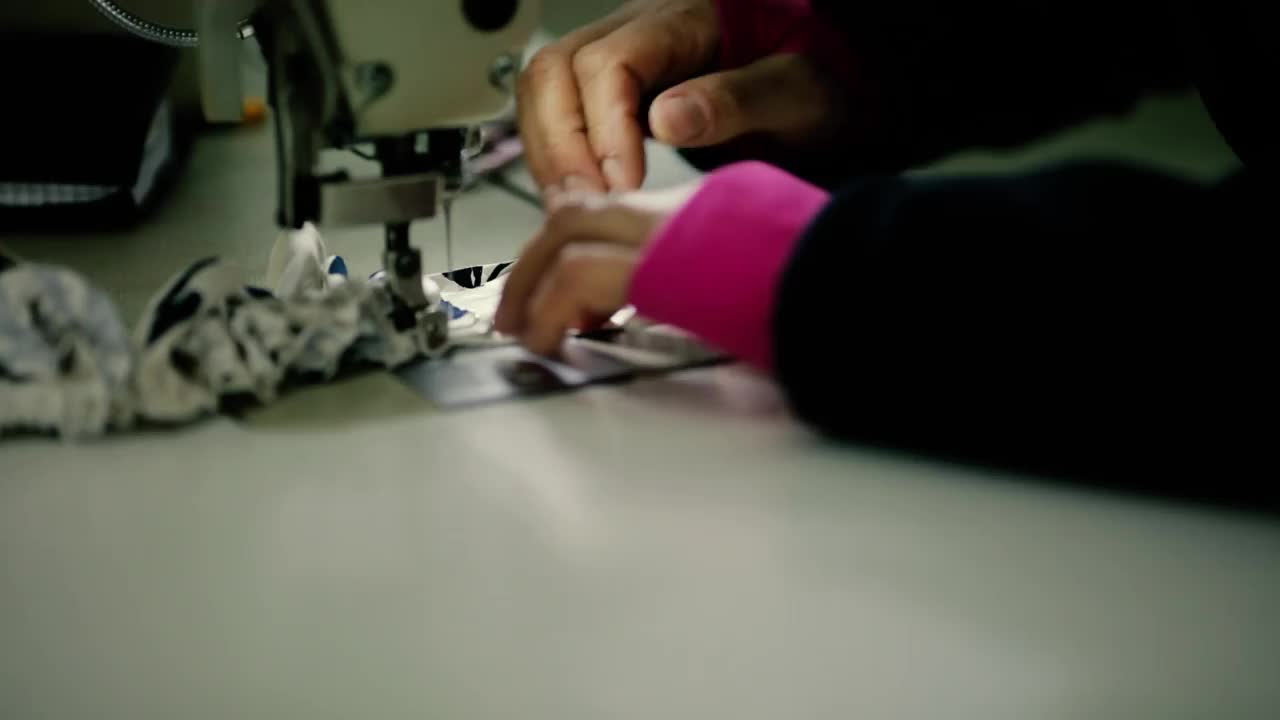 浅景深(选择性聚焦)镜头，一位在纺织厂电动缝纫机上工作的高级妇女的双手。视频素材
