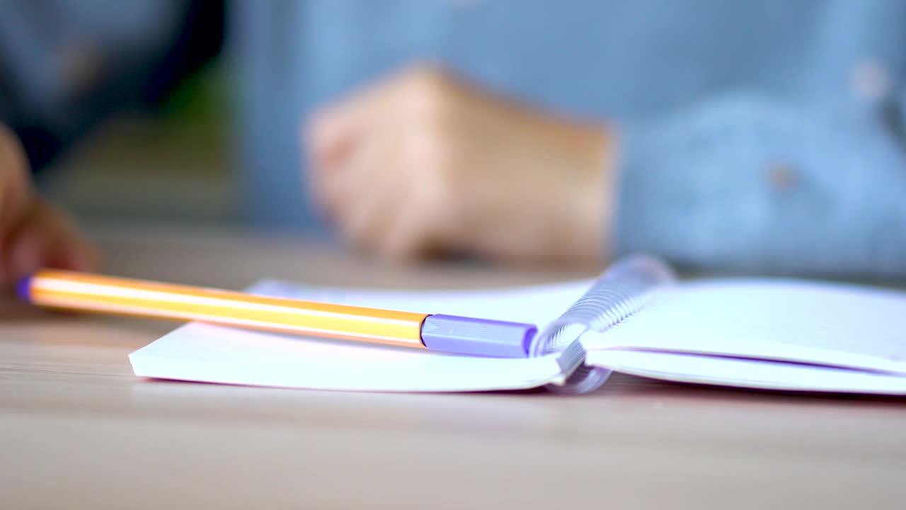 在一张轻便的桌子上，弹簧上放着一本打开的笔记本。黄色的笔在笔记本上。关闭视图。视频素材