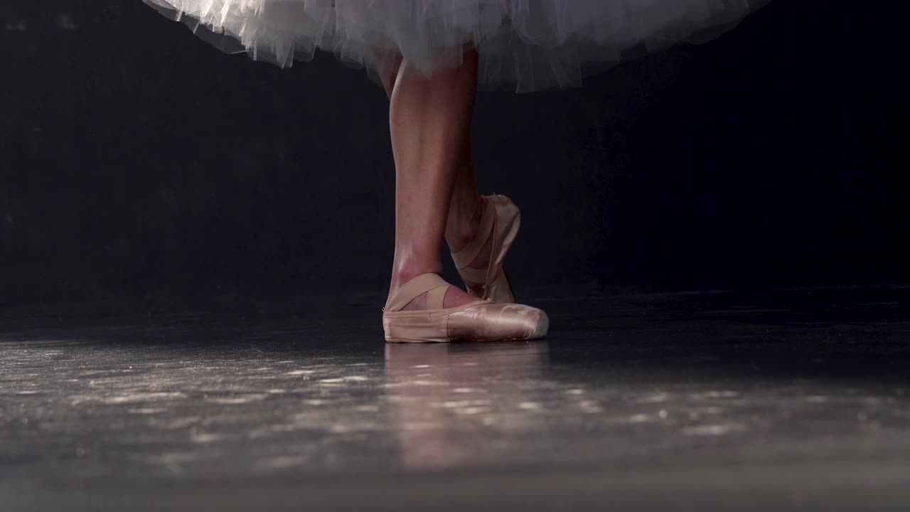 地面水平拍摄的一个古典芭蕾舞者，在一个黑色的舞台上跳舞，与她的脚和尖头鞋的观点视频下载