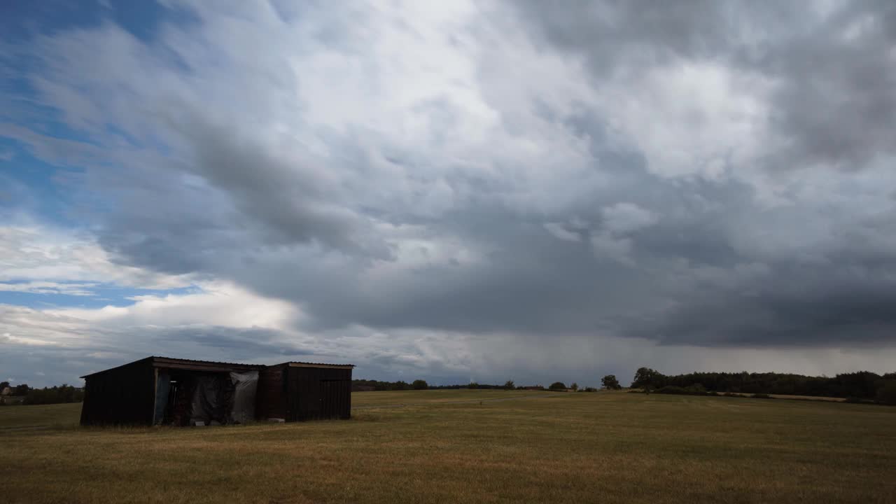 暴风雨的云移动在时间的推移和雨从不同的角度与谷仓的田野视频素材