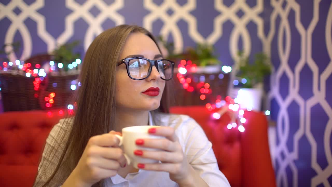 年轻女子坐在咖啡馆喝咖啡。慢动作视频素材