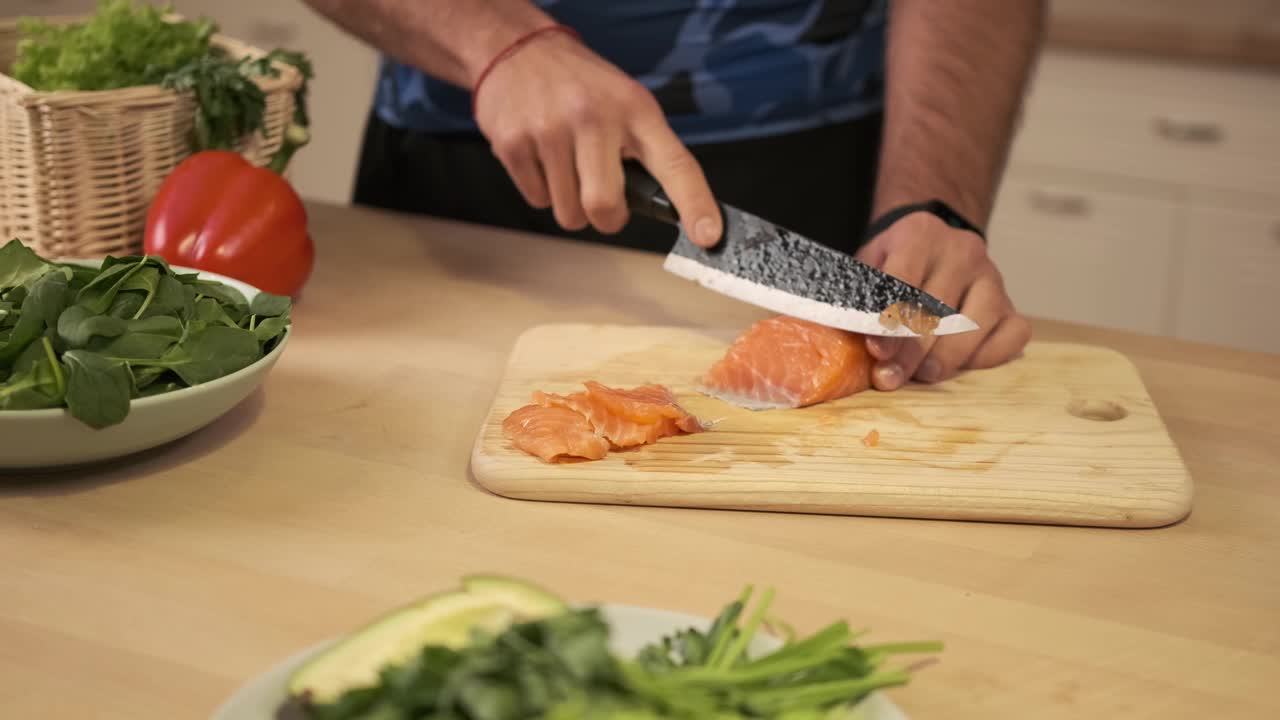 做一盘鲜鱼。厨师用锋利的钢刀在切菜板上把新鲜的鲑鱼或鳟鱼切成薄片。在厨房里准备食物。视频素材