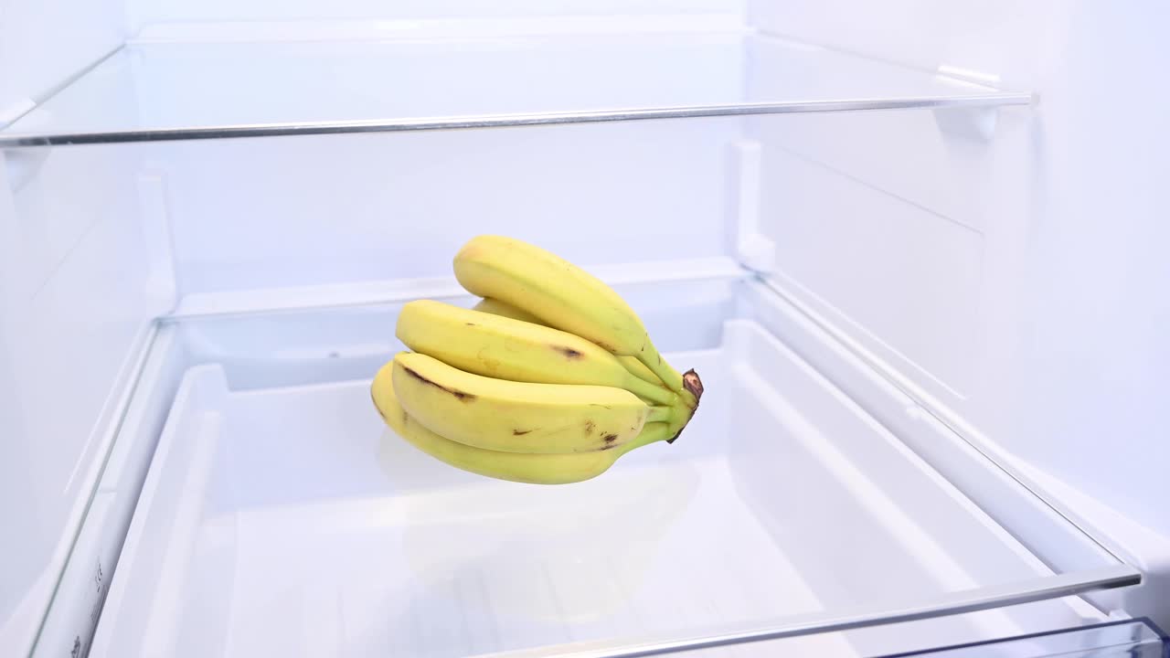 一个男人从冰箱里拿出一串香蕉。视频下载