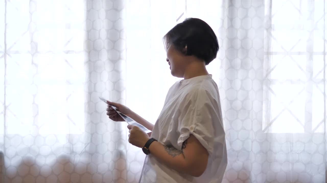 一名亚洲孕妇在家里的床上抱着并看着她婴儿的超声波扫描视频下载