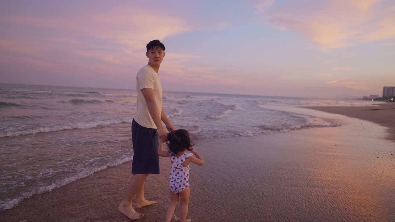 亚洲父亲玩和散步与可爱的女儿度假在海滩在黄昏时间视频素材