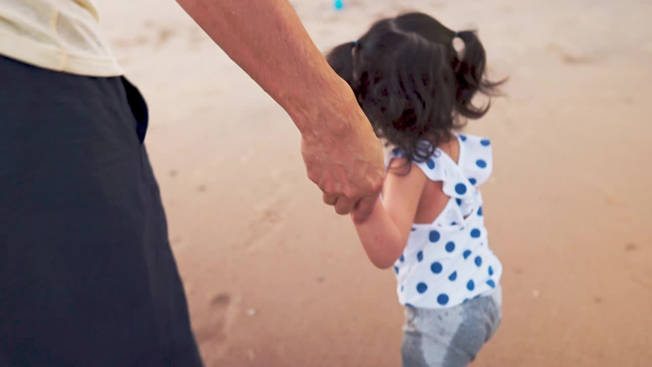 父亲和可爱的女儿在海滩上度假和散步视频素材