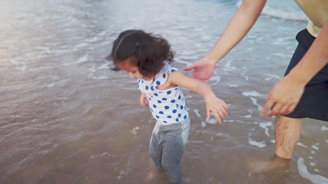 亚洲父亲玩和散步与可爱的女儿在海滩度假视频素材
