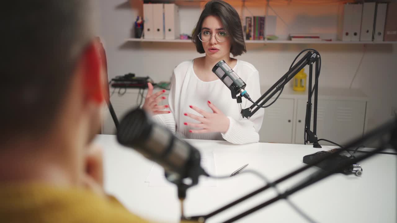 一名千禧一代女性在播客演播室采访一位面目全的男性嘉宾视频素材