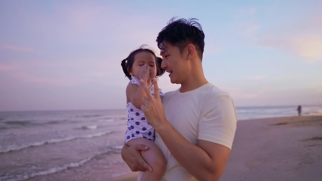 黄昏时分，父亲抱着女儿在海滩上散步视频素材