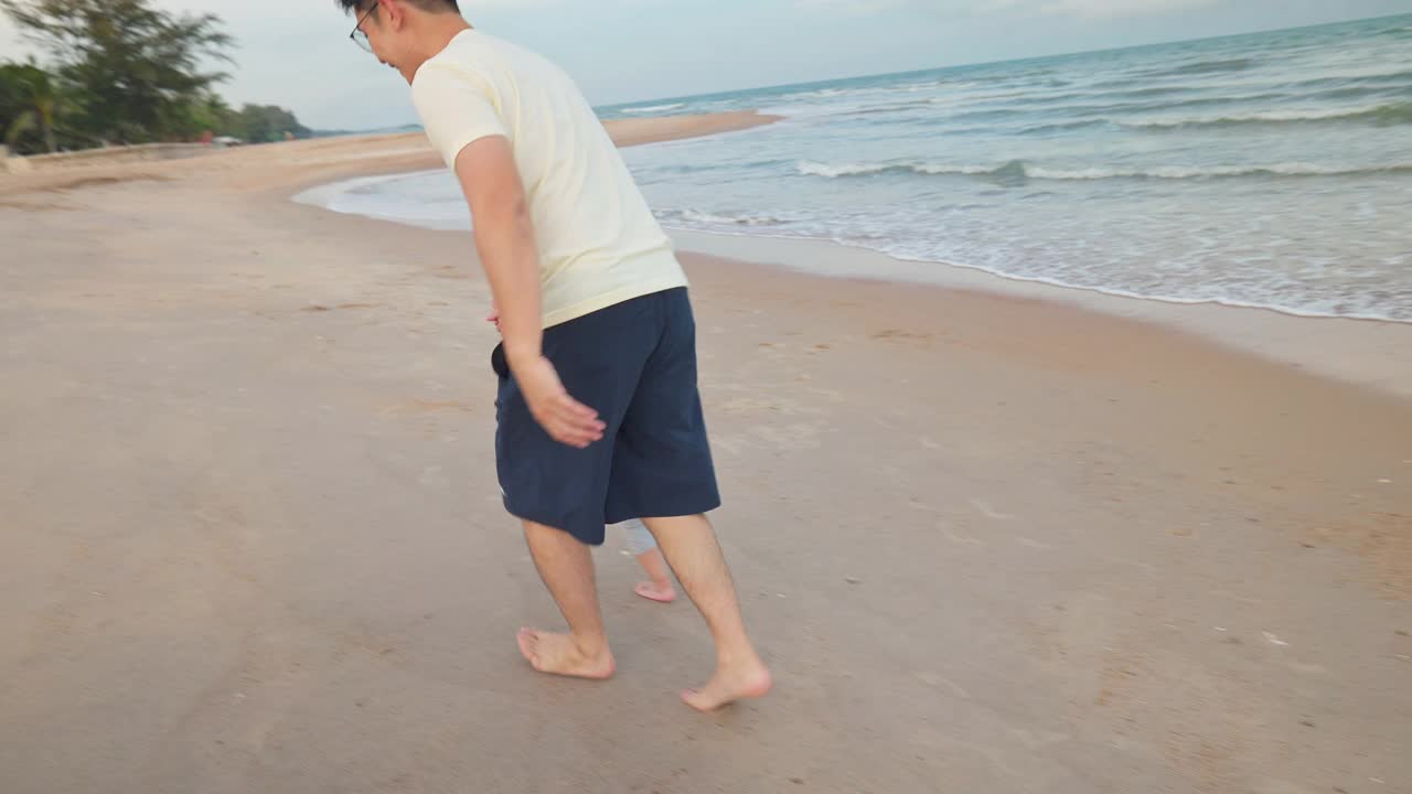 亚洲父亲玩和散步与可爱的女儿在海滩度假视频素材