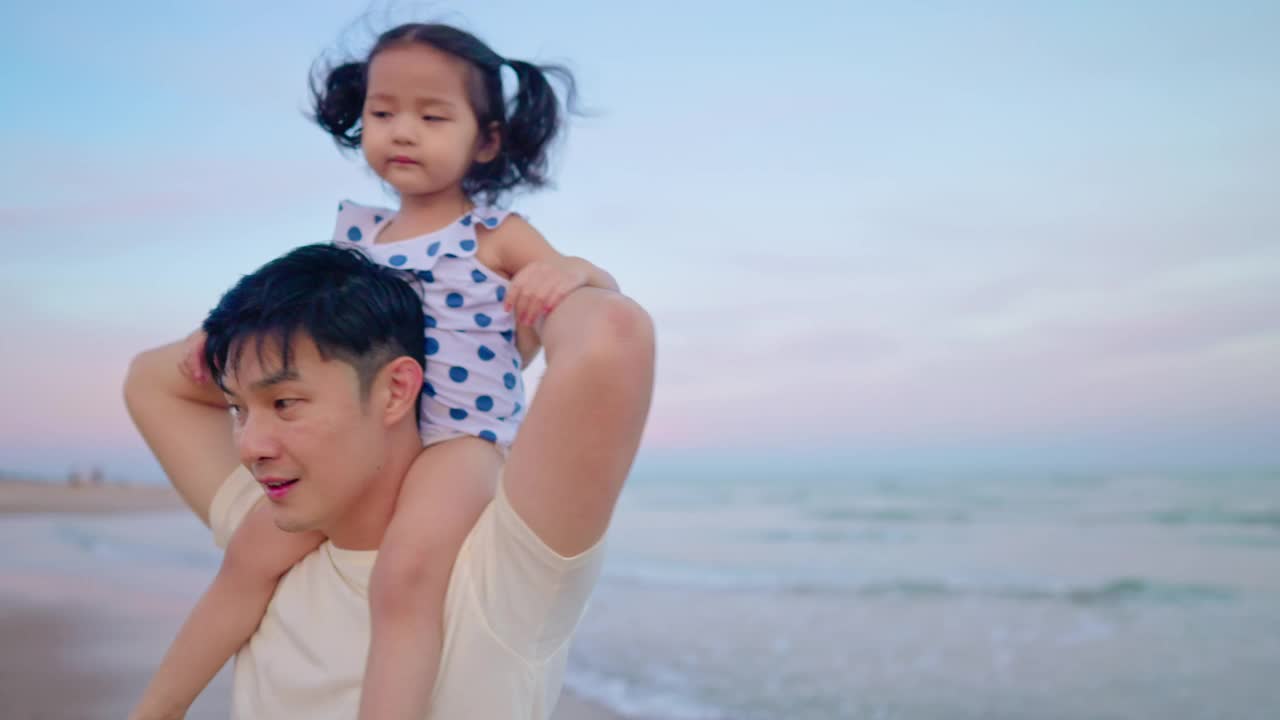 亚洲可爱的女儿坐在父亲的肩膀，而散步在海滩上度假的白天时间视频素材