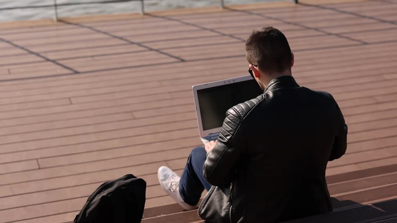 一个年轻人在城市散步时使用笔记本电脑视频素材