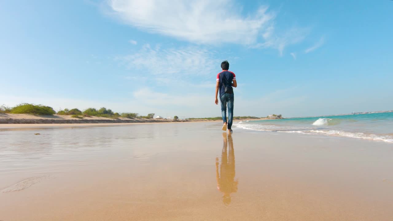 在印度古吉拉特邦的Byet Dwarka，一个年轻的印度男子走在海滩上视频素材
