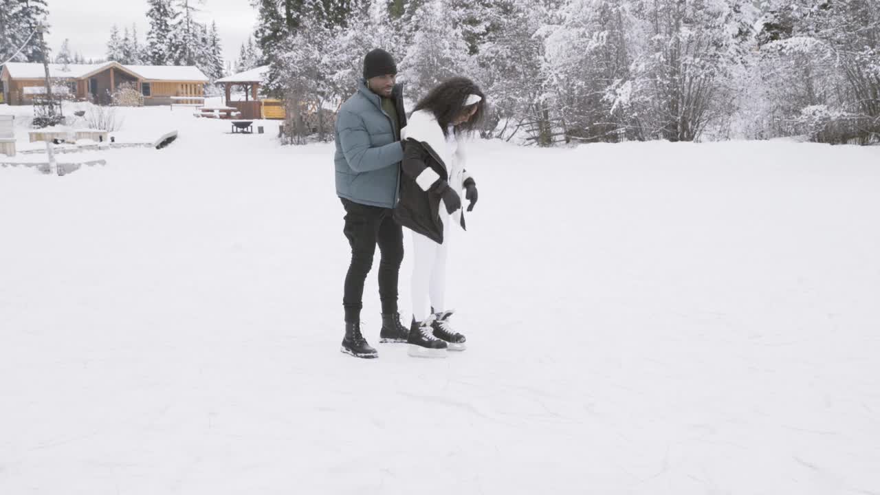 一个女人试图在结冰的湖面上滑冰，差点摔倒，被她的男朋友接住了。视频下载