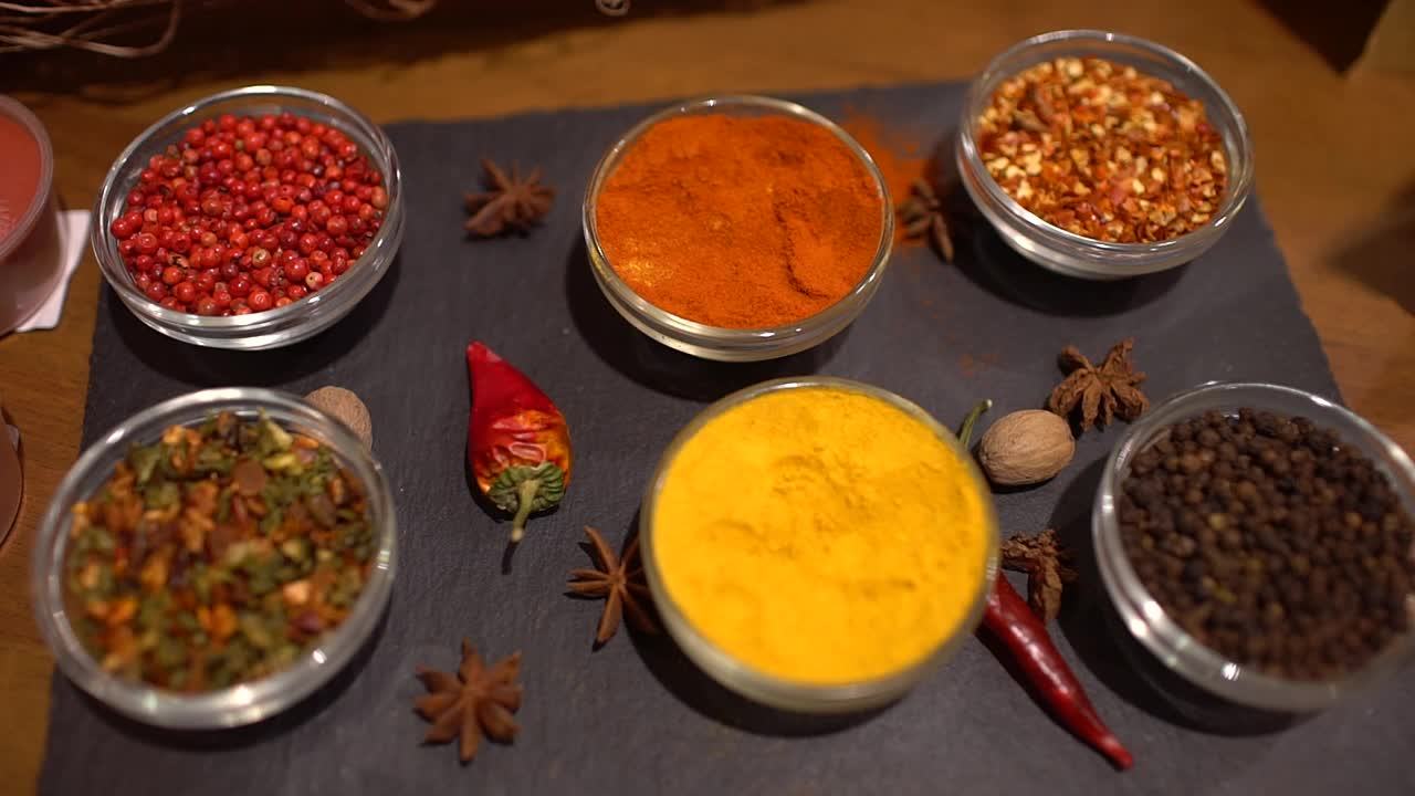 香料。餐桌上有各种印度香料。不同的香料和香草背景，调味料的分类。烹饪原料,味道。红辣椒，藏红花，红辣椒，肉豆蔻，黑胡椒，豌豆视频素材