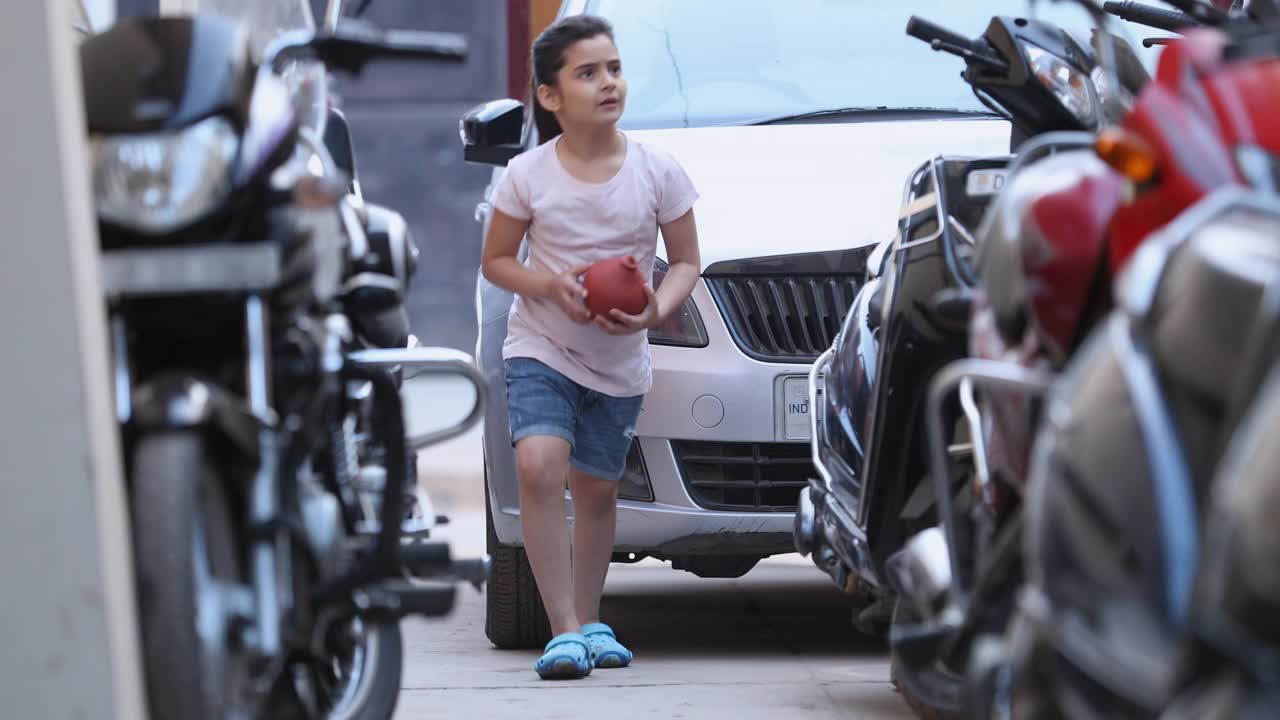 中镜头的女孩抱着储蓄罐在城市的道路上奔跑视频下载