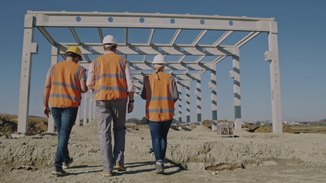 SLO MO阅读三名建筑工人在建筑工地行走的镜头视频素材