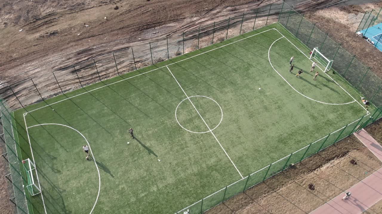 男孩子们踢足球，在足球场上训练。人们在夏天踢足球。足球场，无人机鸟瞰图视频素材