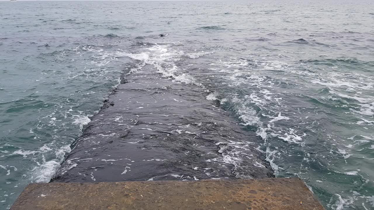 波浪在上面翻滚的石头码头。多云的天气，波涛汹涌的大海。视频下载