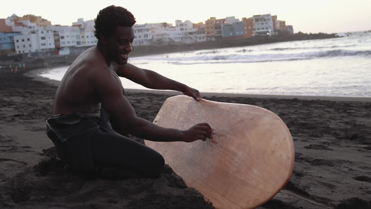 非洲冲浪者在海滩上给冲浪板打蜡视频下载