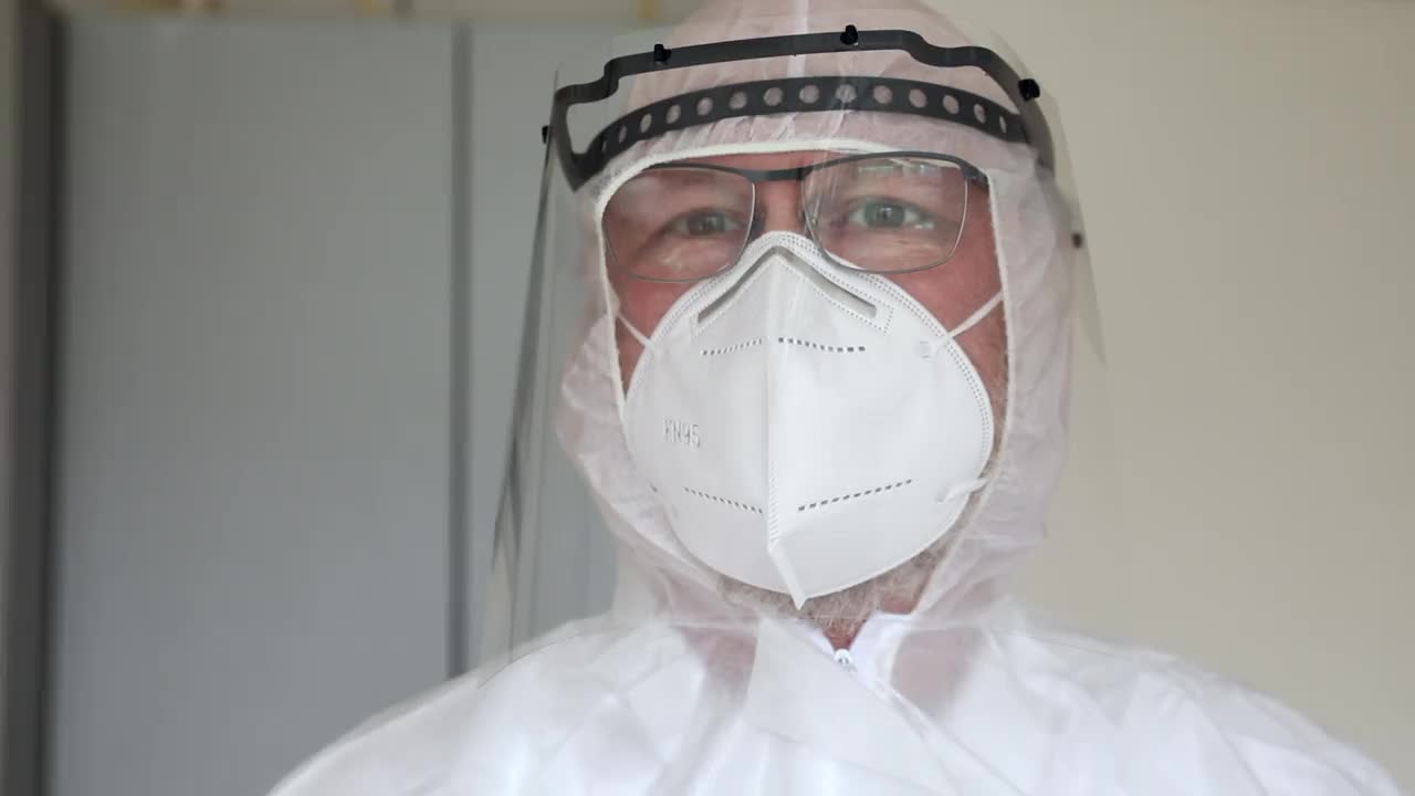 特写医生戴着防护FFP2口罩，面罩和医疗防护服。视频素材
