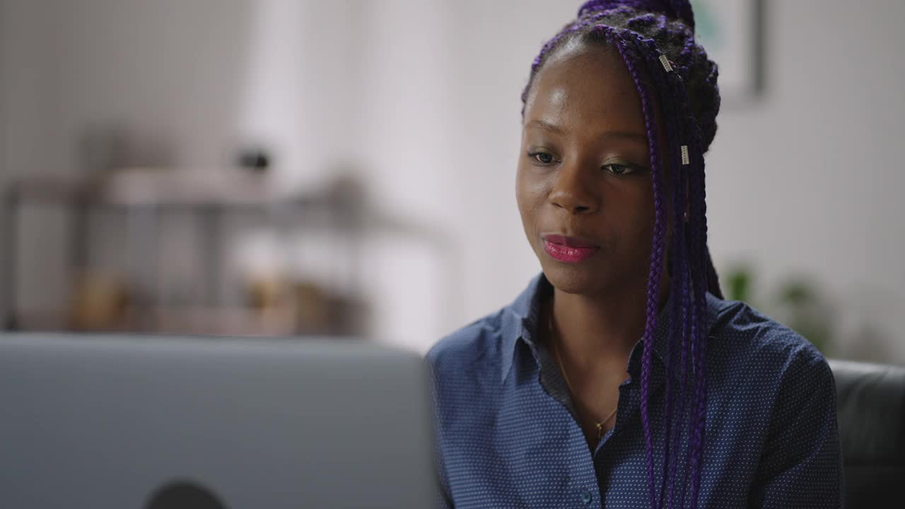 年轻的美国黑人妇女远程面试，女士是通过视频聊天沟通坐在家里，使用笔记本电脑与互联网视频素材