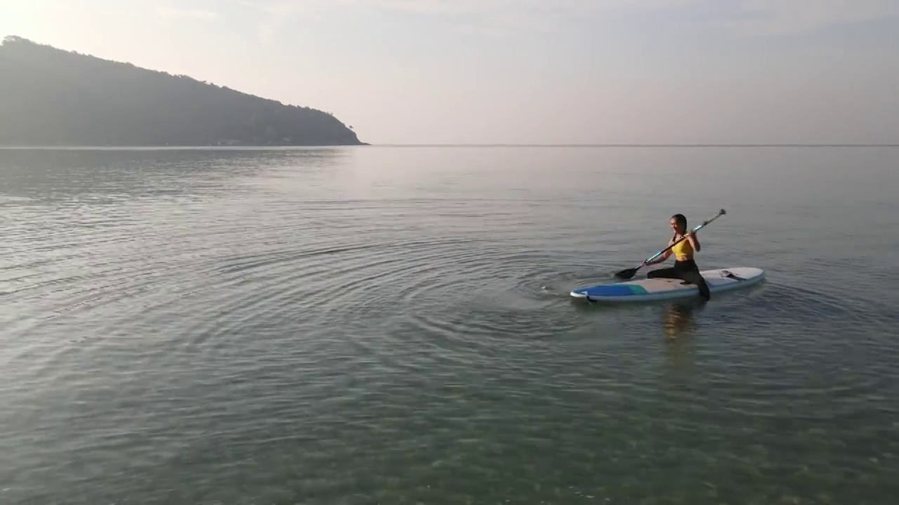 鸟瞰图的早晨瑜伽练习与柔和的阳光在海上。视频下载
