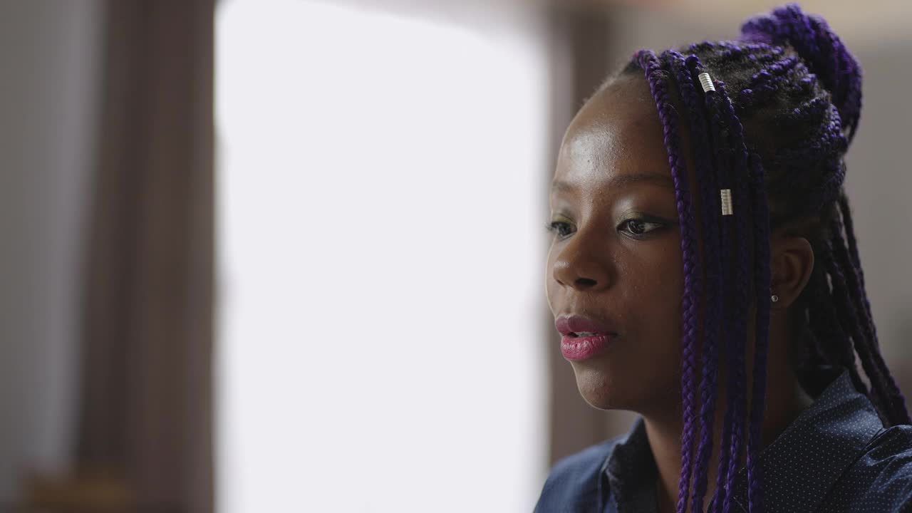 一位年轻的美国黑人妇女正在用笔记本电脑视频聊天，看着网络摄像头，回答问题视频素材