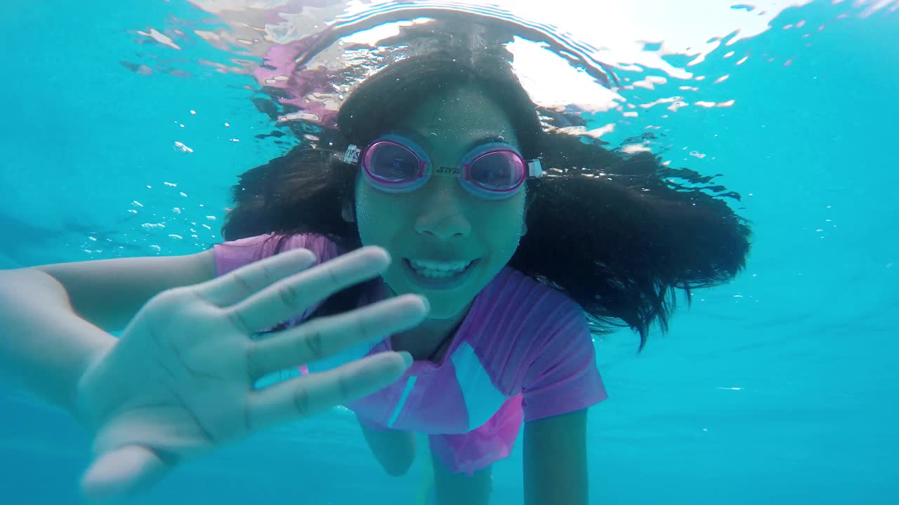 快乐的亚洲女孩跳进泳池游泳，在水的视野。暑假的概念。视频下载