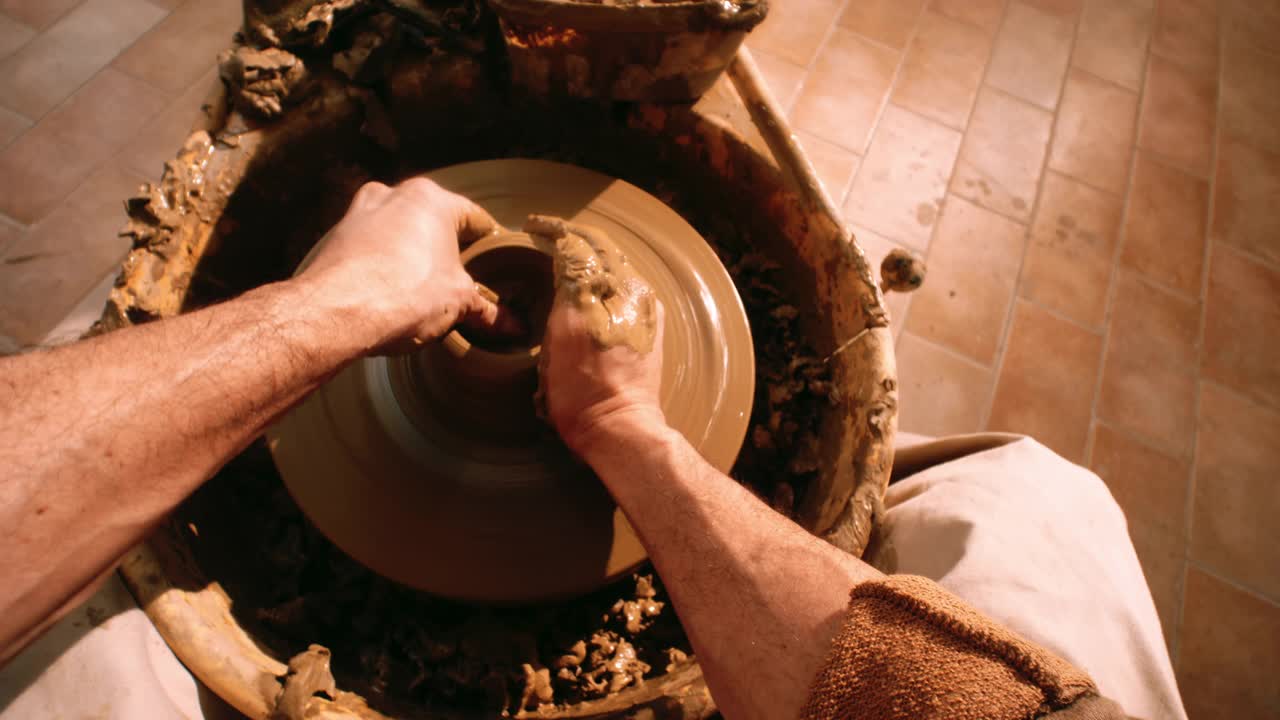POV一个男性陶工的手拉着一堵墙上的锅在轮子上旋转视频素材