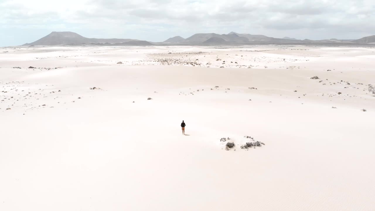 一名男子在富埃特文图拉岛的沙丘沙漠中独自沉思。西班牙。想象一个富尔特文图拉的杜纳斯的街景。视频素材
