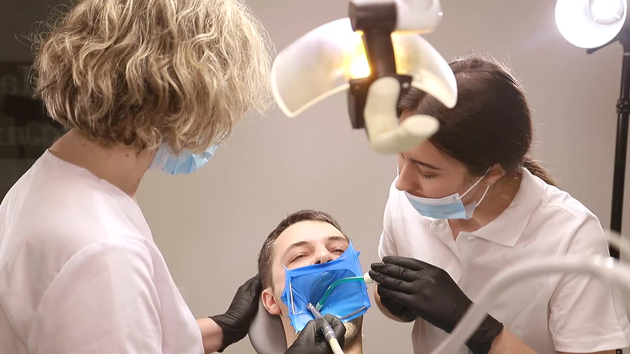 一个人去看牙医，牙医治疗病人的牙齿视频素材