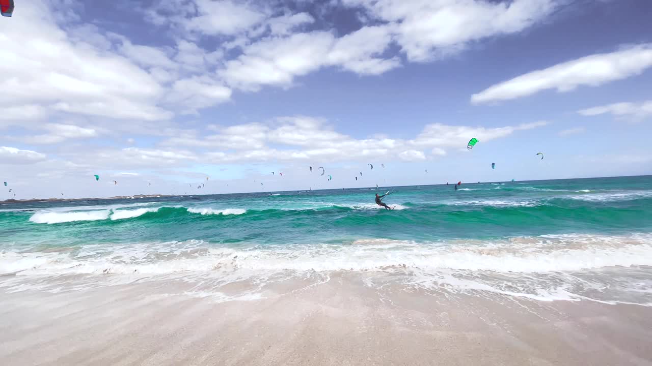 西班牙多风的富埃特文图拉岛，一大群人在玩风筝滑板。视频素材