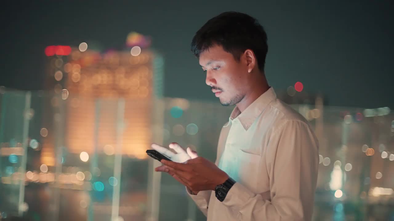 亚洲人晚上在城市里使用手机视频素材