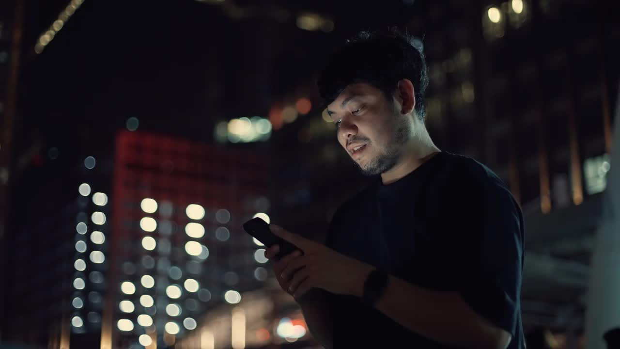 男人晚上在城市里用智能手机视频素材
