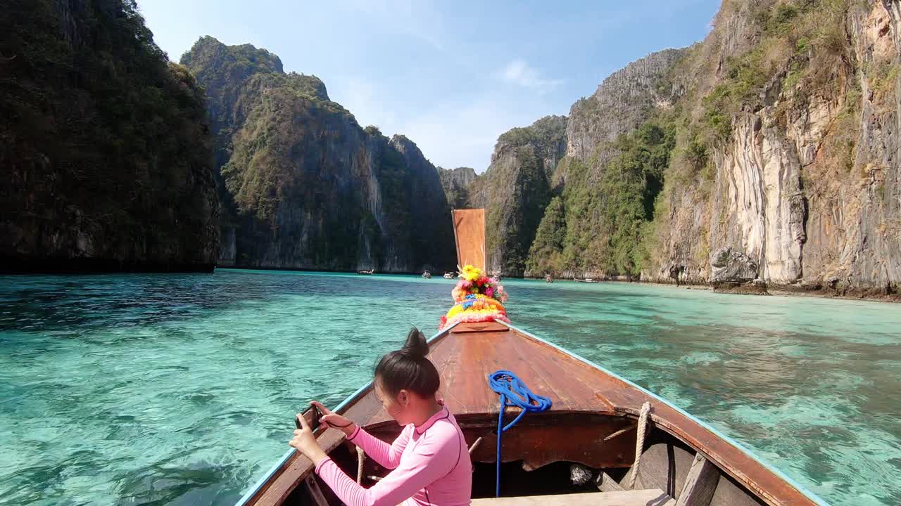 在泰国甲米省披披岛，一名亚洲女子坐在泰国的士船上，用智能手机拍摄安达曼海上的热带岛屿。适合旅游休闲。4 k慢动作。视频下载