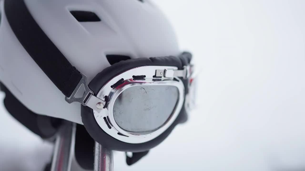 滑雪头盔和护目镜的特写与白色的雪在背景。滑雪场的户外冬季运动装备。视频素材