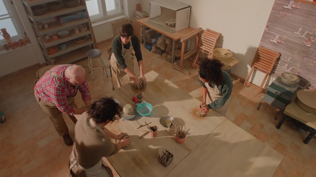 三个年轻人正在陶艺室里学习如何楔粘土视频素材