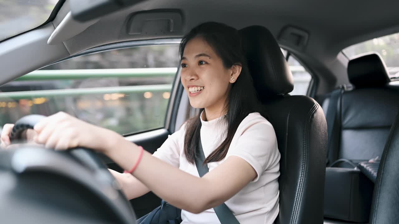 亚洲女性在开车上班的时候会在车上使用手机的无线蓝牙视频下载
